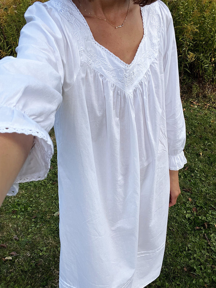 Person wearing a white dress with lace details outdoors on a grassy background