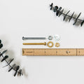 Bolt, nut, and washer hardware set with zinc and brass finish options — mounting components for leather wall straps, suspended storage systems, and wall-mounted wood rails with ruler for size reference.