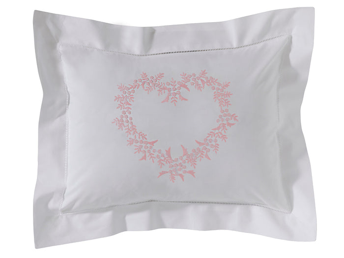 White pillow with pink floral wreath design on a white background