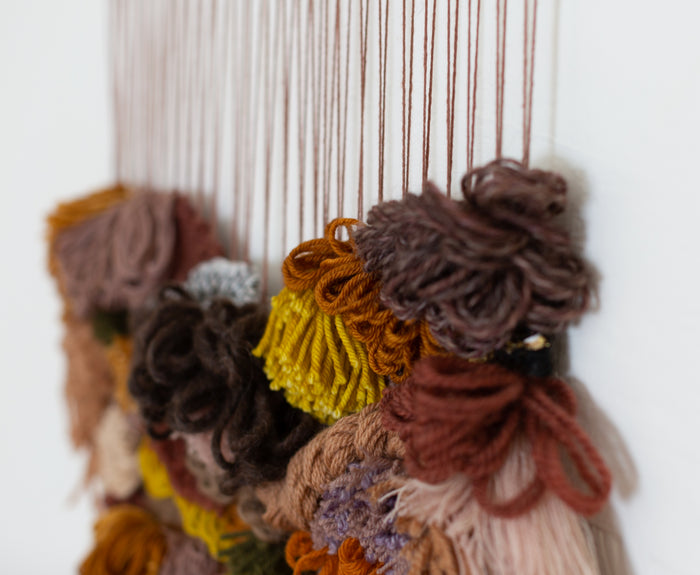 Macro detail of Cedarville showing textured wool clusters and cascading fringe — contemporary woven wall sculpture.