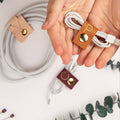 Nicotine leather cord holder with customized P initial, artisan-crafted by Keyaiira for neatly securing white charging cables, phone cords, USB wires and portable tech accessories