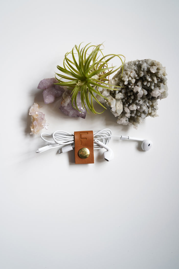 Nicotine leather cable keeper styled with natural botanicals, thoughtfully crafted by Keyaiira for charger cord storage, electronics organization, travel tech and clutter-free workspaces
