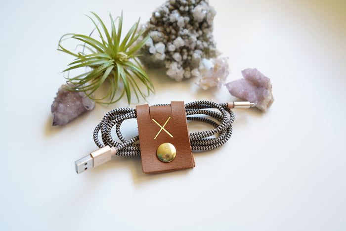 Walnut leather cord wrap securing a braided electronics cable, carefully designed by Keyaiira for computer cords, charging cables, device accessories and streamlined cable storage