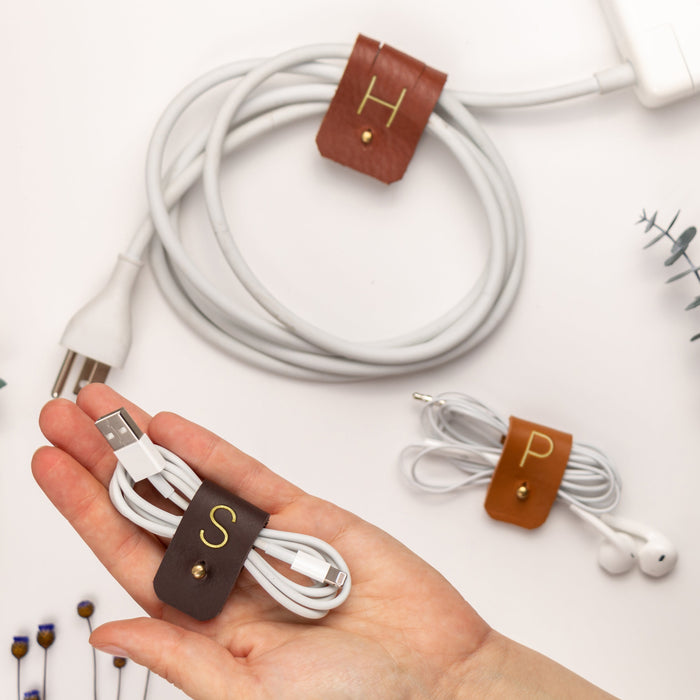 Chocolate full-grain leather cord holder with S initial, crafted by Keyaiira for organizing charging cables, wired earbuds, USB cords and small electronics while keeping everyday tech neatly bundled