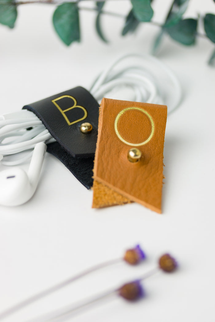 Black and Nicotine leather cord keepers with custom B and O letters, individually crafted Keyaiira cable holders for headphones, phone chargers, device wires and everyday tech organization