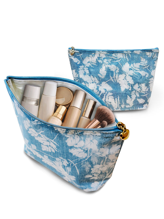 Blue floral makeup bag with cosmetic items on a white background