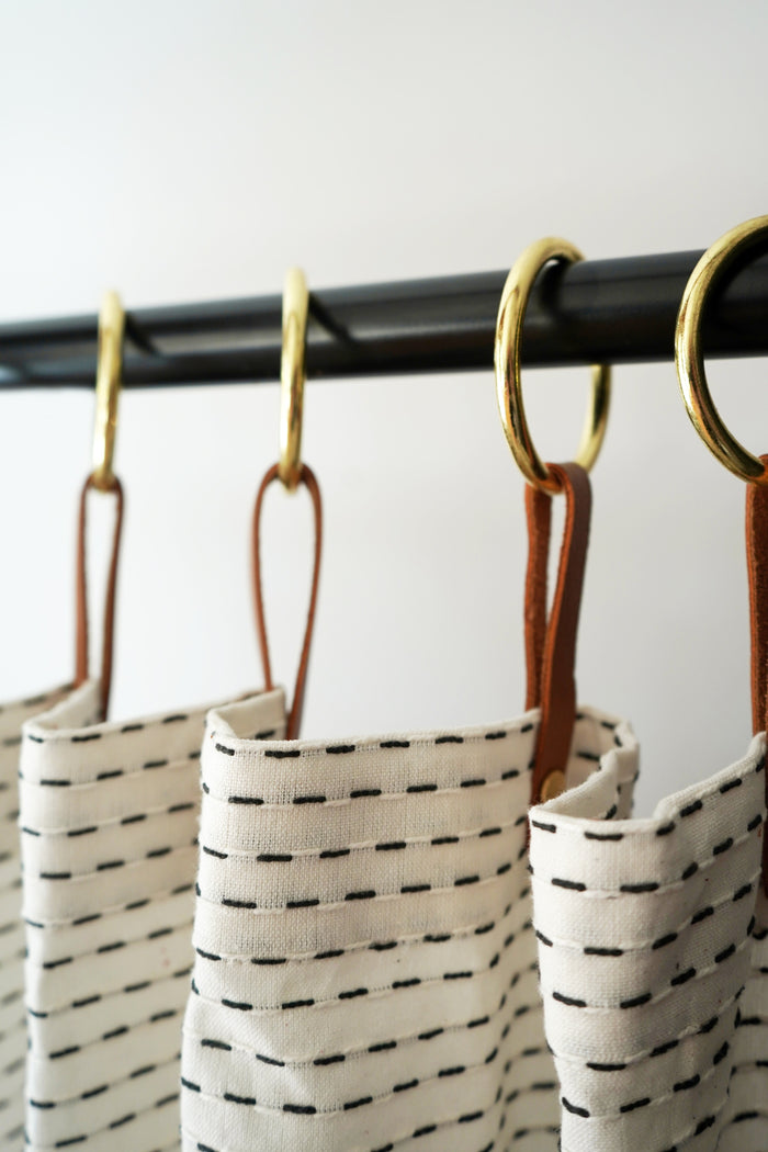 Set of nicotine leather shower curtain hangers with Brass rings used on a fabric shower curtain, creating a streamlined monochromatic look ideal for modern bathrooms.
