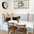 Keyaiira custom wide leather wall straps in warm tan securing upholstered bench cushions to a white shiplap dining nook wall — handcrafted vegetable-tanned leather cushion straps add modern farmhouse style and functional wall-mounted seating support with clean, minimalist design.