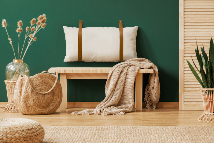 Keyaiira tan leather wall straps holding a decorative pillow above a woven bench  handcrafted leather mounting straps for custom decor installations.