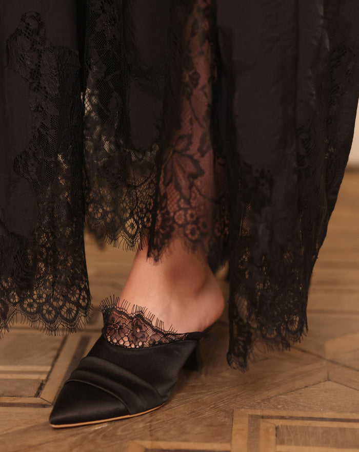 Close-up of the slipper on one foot, highlighting the delicate French lace adornment and meticulous craftsmanship.
