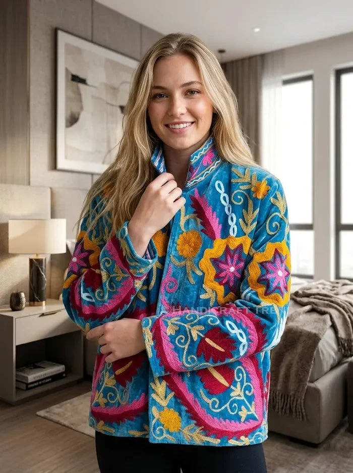 Woman wearing a colorful embroidered jacket in a modern living room.