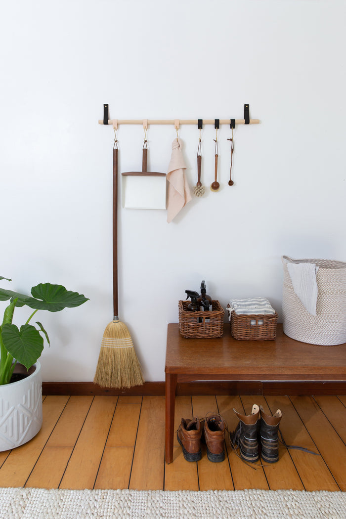 Kitchen wall rail with hooks and leather loops above prep counter — functional wall storage for utensils, towels, and cookware.