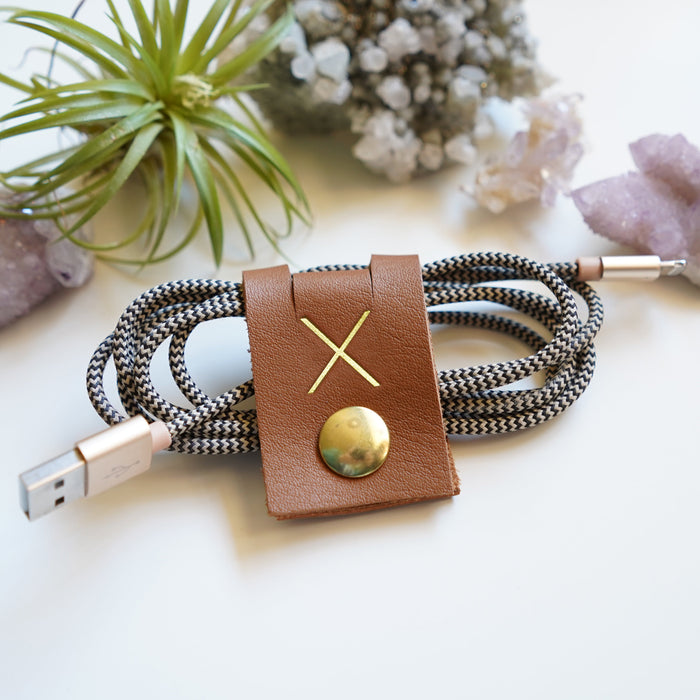 Handmade Cognac leather cord keeper wrapped around a braided charging cable, large snap closure cable organizer for USB cords, power cables, device chargers and clutter-free storage by Keyaiira