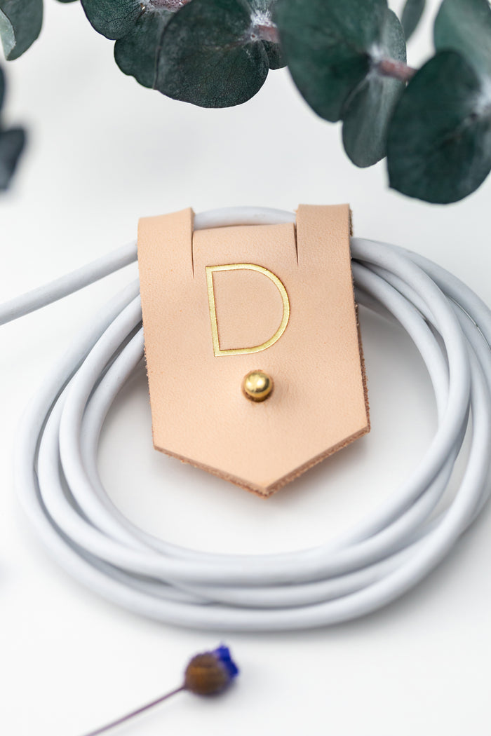 Personalized Veg Tan leather charger cord keeper with D initial, Stud & Post closure for coiled charging cables, USB cords, device cables and compact electronics storage by Keyaiira