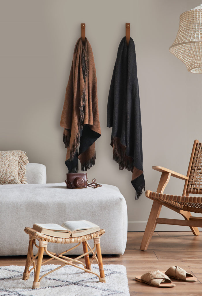 Minimalist home decor using Keyaiira large leather straps as blanket holders for functional wall organization.