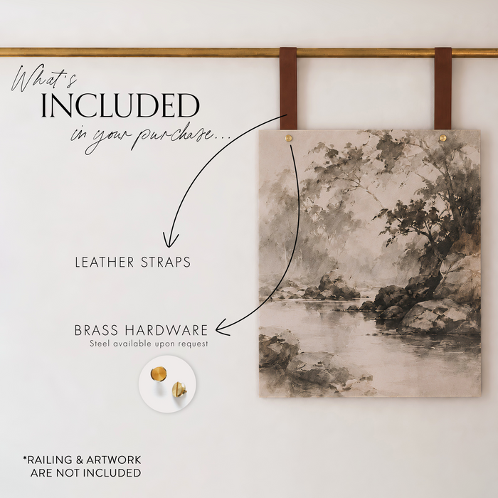 A canvas wall art print with a monochrome landscape painting is displayed hanging from two brown leather straps on a gold rod against a white wall. Text on the left lists included items: leather straps, brass hardware, and a small round sample of brass hardware.