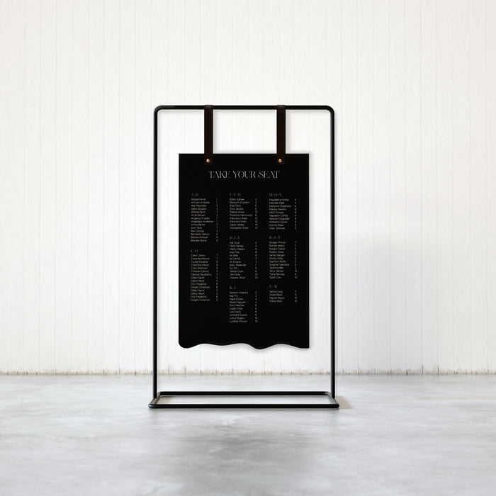 Keyaiira handmade signage hanger in black leather featured in an elegant wedding seating chart display on minimalist metal frame.