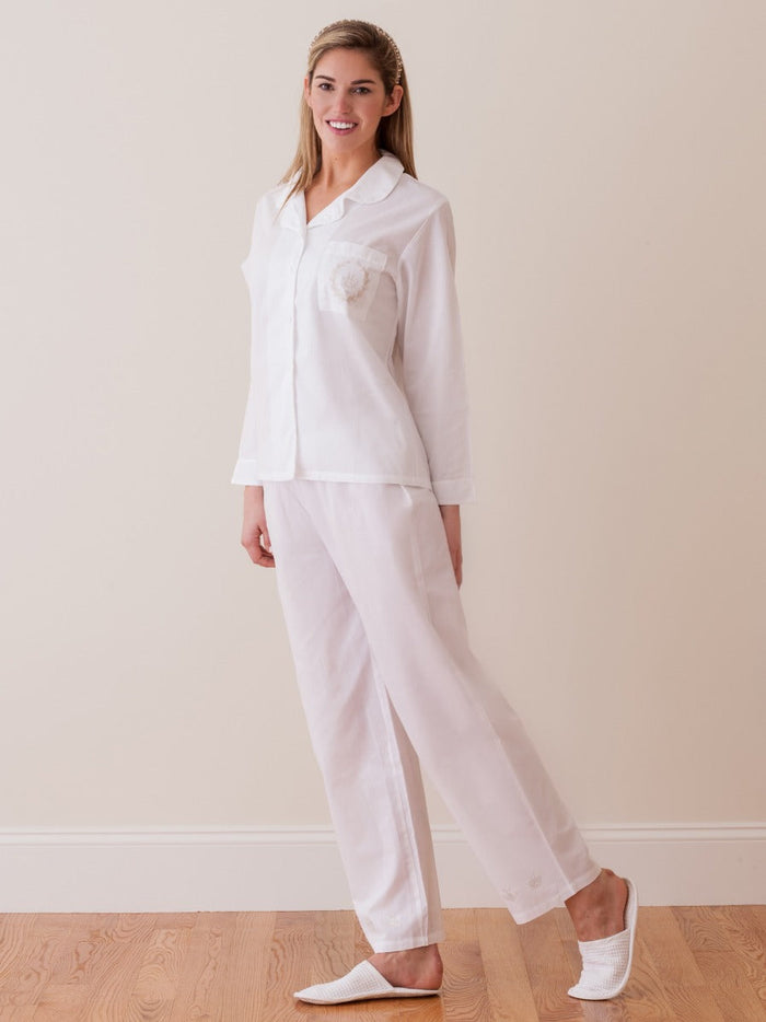 Woman wearing a white pajama set against a plain background