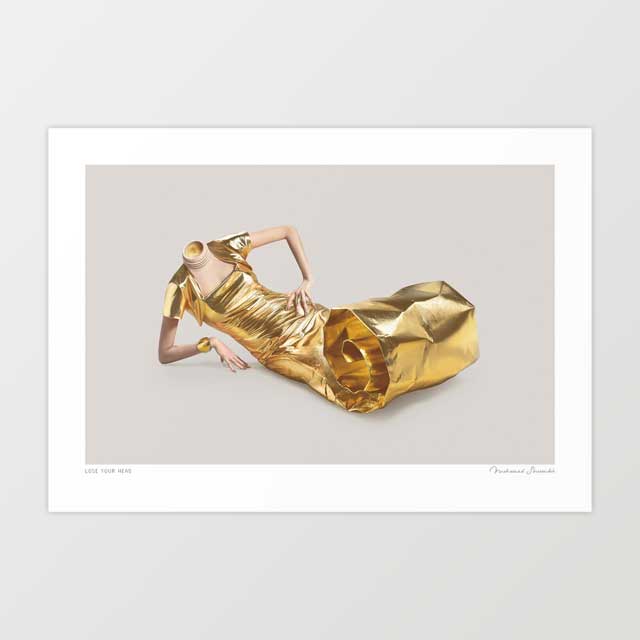 Lose Your Head surreal art print horizontal — headless woman reclining in a sculptural crumpled gold lamé dress with geometric folds gold cuffs and gold shoes in a languid composed pose against a soft warm grey studio background, surreal luxury fashion editorial print for dressing rooms boutiques and bold interiors