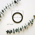 Matte black ring shown with 2.5-inch size reference — minimalist metal hardware for wall-mounted leather loops and hanging storage.