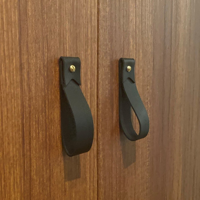 Keyaiira black leather cabinet pulls on wood doors handcrafted leather loop handles with brass screws for modern minimal hardware design.