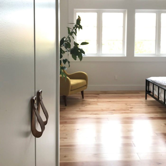 Keyaiira brown leather cabinet pulls on white closet doors handcrafted loop handles for modern Scandinavian-inspired interiors.