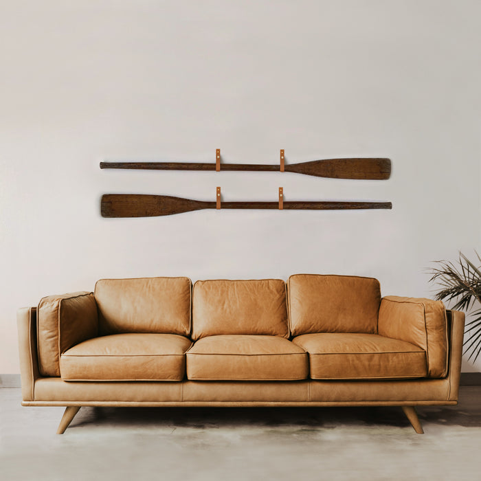 Keyaiira leather wall strap styled in modern living room above leather sofa — minimalist functional wall decor with solid brass hardware accent.