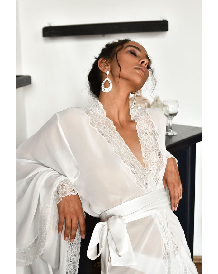 Woman in white bridal robe seated beside a piano