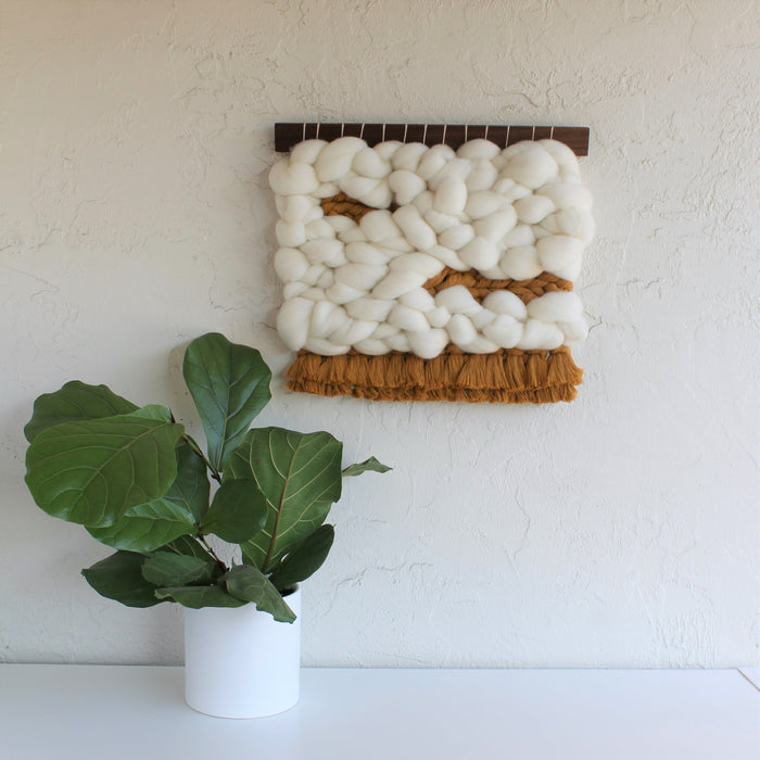 Keyaiira handcrafted woven wall hanging made with chunky white wool roving and warm brown fringe, showcasing organic texture and modern minimalist fiber art