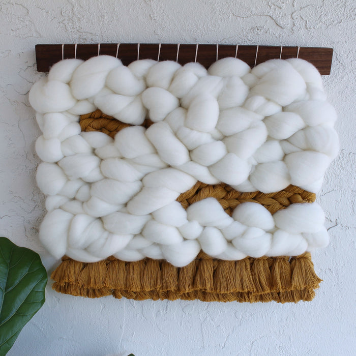 Keyaiira handcrafted wool wall hanging with oversized braided white fibers and layered brown fringe, showcasing natural materials and sculptural textile design