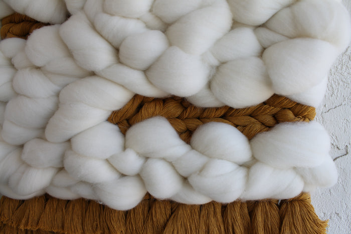 Keyaiira handcrafted wall hanging featuring thick handwoven white wool roving with a subtle center opening and soft brown fringe, showcasing modern textured fiber art
