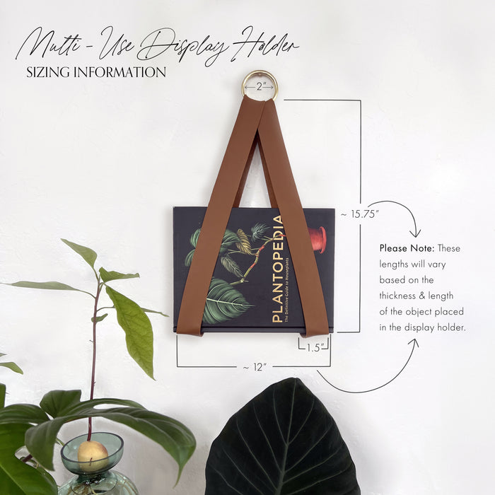 Keyaiira multi-use leather display holder sizing information image showing measurements and proportions, featuring a brown leather strap with brass ring holding a Plantopedia book on a white wall.