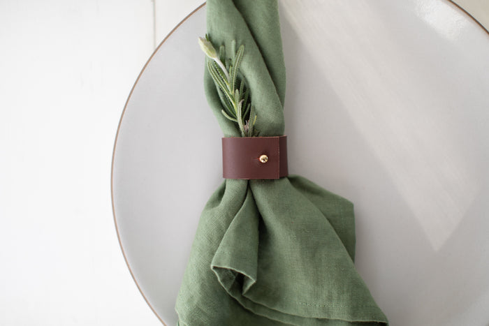 Handcrafted Leather Napkin Ring by Keyaiira in Walnut minimal modern tableware accessory with brass hardware, styled on a ceramic plate with a green linen napkin for elegant dining decor.