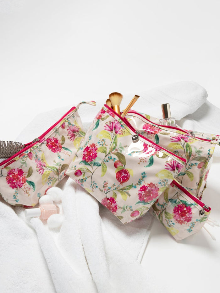 Floral makeup bag with brushes and a perfume bottle on a white surface