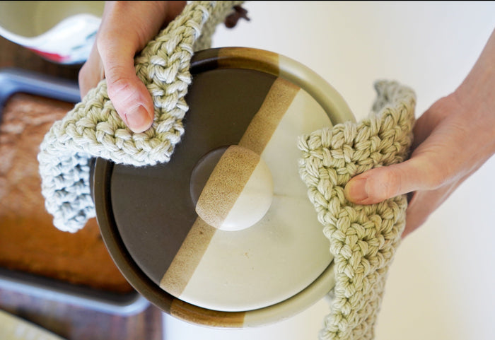 Handcrafted cotton potholder protecting tabletop from hot cookware — thick woven trivet with leather cord hanger for everyday kitchen use.