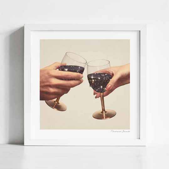Primordial Wine art print framed view — two hands toasting with gold wine glasses containing sparkling star-filled galaxies against a cream background, cosmic romantic anniversary wall art for restaurants boutique hotels and gallery walls