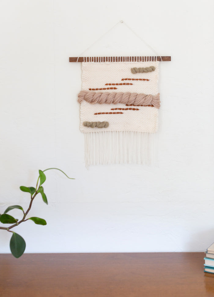 Minimalist living space featuring large woven wall tapestry — Scandinavian-inspired handmade wall art with soft neutral palette.