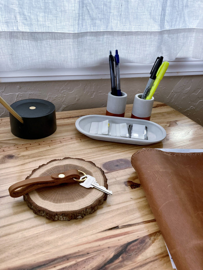 Leather loop keychain styled on wood desk with everyday essentials — slim key holder with brass hardware for modern organization.
