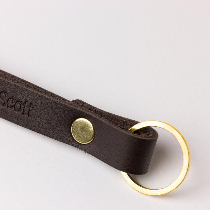 Dark brown leather loop keychain with gold ring — slim everyday carry key fob with simple modern design.