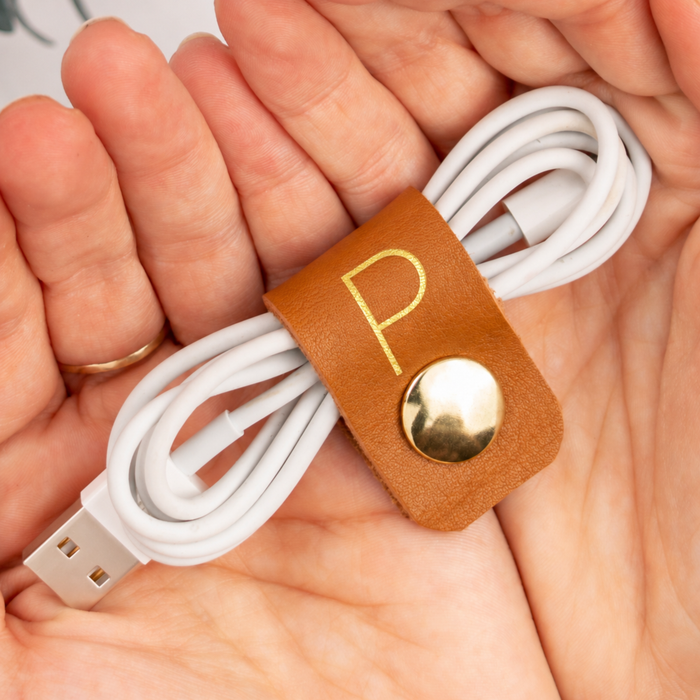 Personalized leather charger cord keeper with P initial, handcrafted compact cable holder with brass snap for white charging cables, USB cords, device chargers and travel storage by Keyaiira