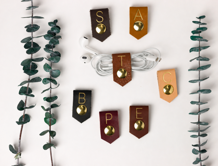 Artisan-crafted leather cable holders with customized letters and assorted Keyaiira color options, compact cord organizers for earbuds, charging cables, electronics and tidy desk storage