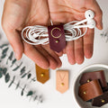 Wine full-grain leather earbud keeper with custom C initial, crafted by Keyaiira with minimal brass stud & post hardware for wired headphones, small cords and tangle-free everyday storage