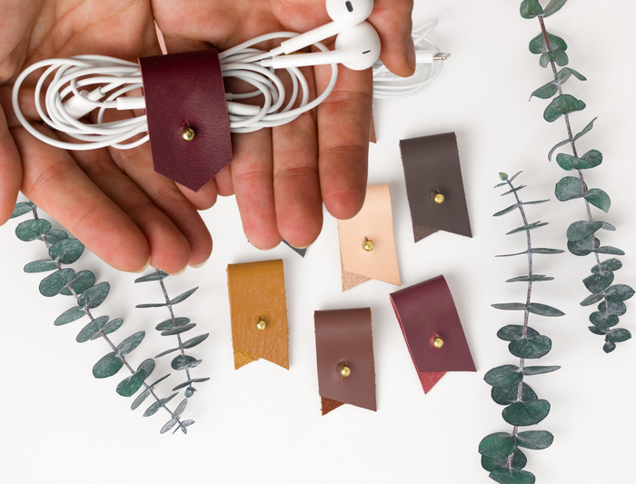 Custom-lettered Wine leather cord holder displayed with assorted Keyaiira color choices, artisan-made for earbud storage, charging cables, USB cords and organized tech essentials