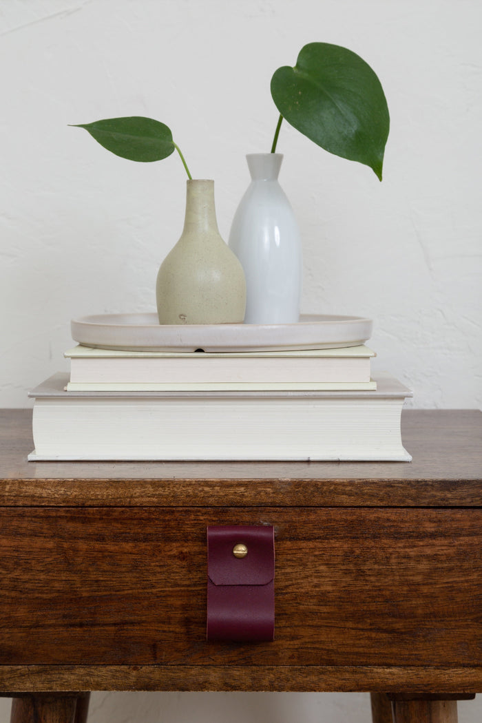 Keyaiira wine leather wide pull installed on a walnut drawer, rich burgundy tone creating a bold handcrafted accent for modern furniture.