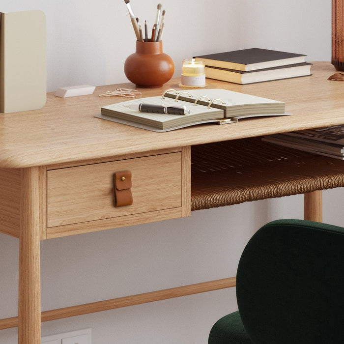 Keyaiira nicotine leather small wide drawer pull with brass hardware installed on a light oak desk drawer, styled with an open planner, candle, and modern workspace décor, handcrafted leather furniture handle for minimalist home offices.