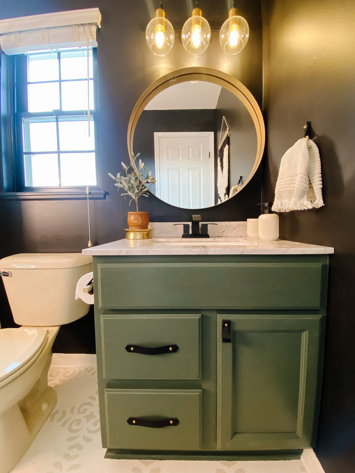 Keyaiira leather pulls in matte black on green vanity drawers artisanal leather cabinet handles complementing bold, modern bathroom design.