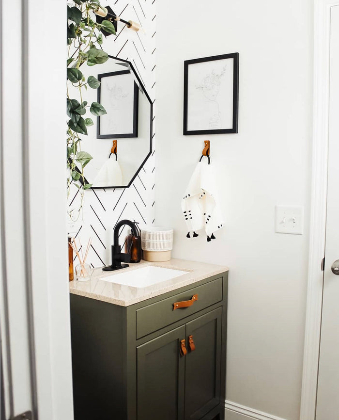 Keyaiira leather pulls in nicotine on green vanity cabinet custom handmade leather hardware bringing natural warmth to a bright modern bathroom.