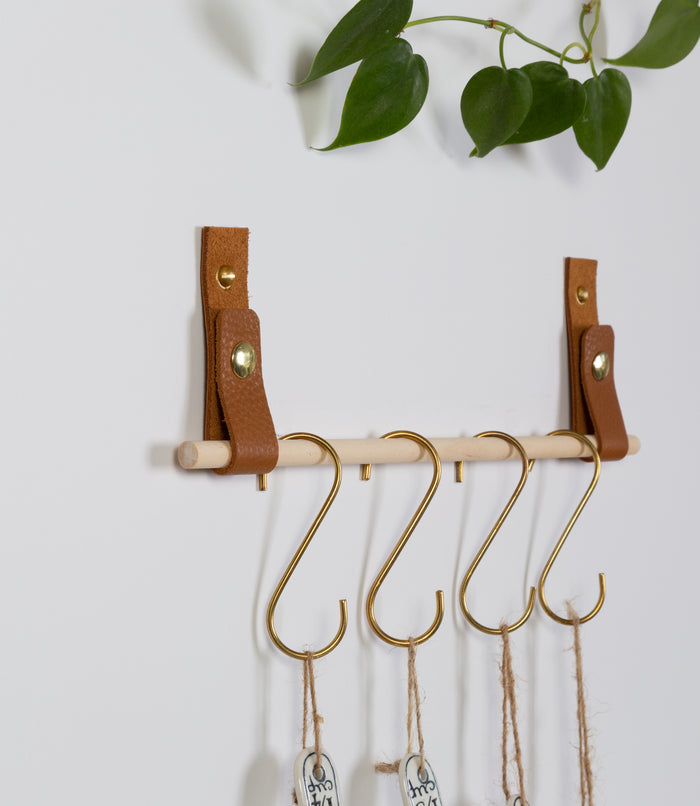 Keyaiira leather wall straps installed in a row on white wall with brass hooks for hanging bags and accessories — modern minimalist wall organizer.
