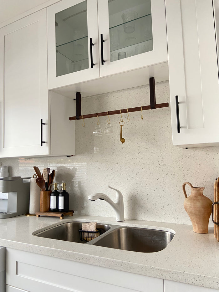 Suspended storage system displayed in white kitchen above sink — wall-mounted hanging rail for modern farmhouse organization.