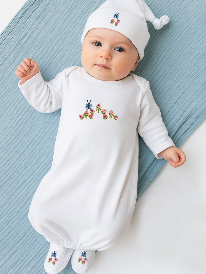 Baby wearing a white outfit with floral embroidery on a blue blanket